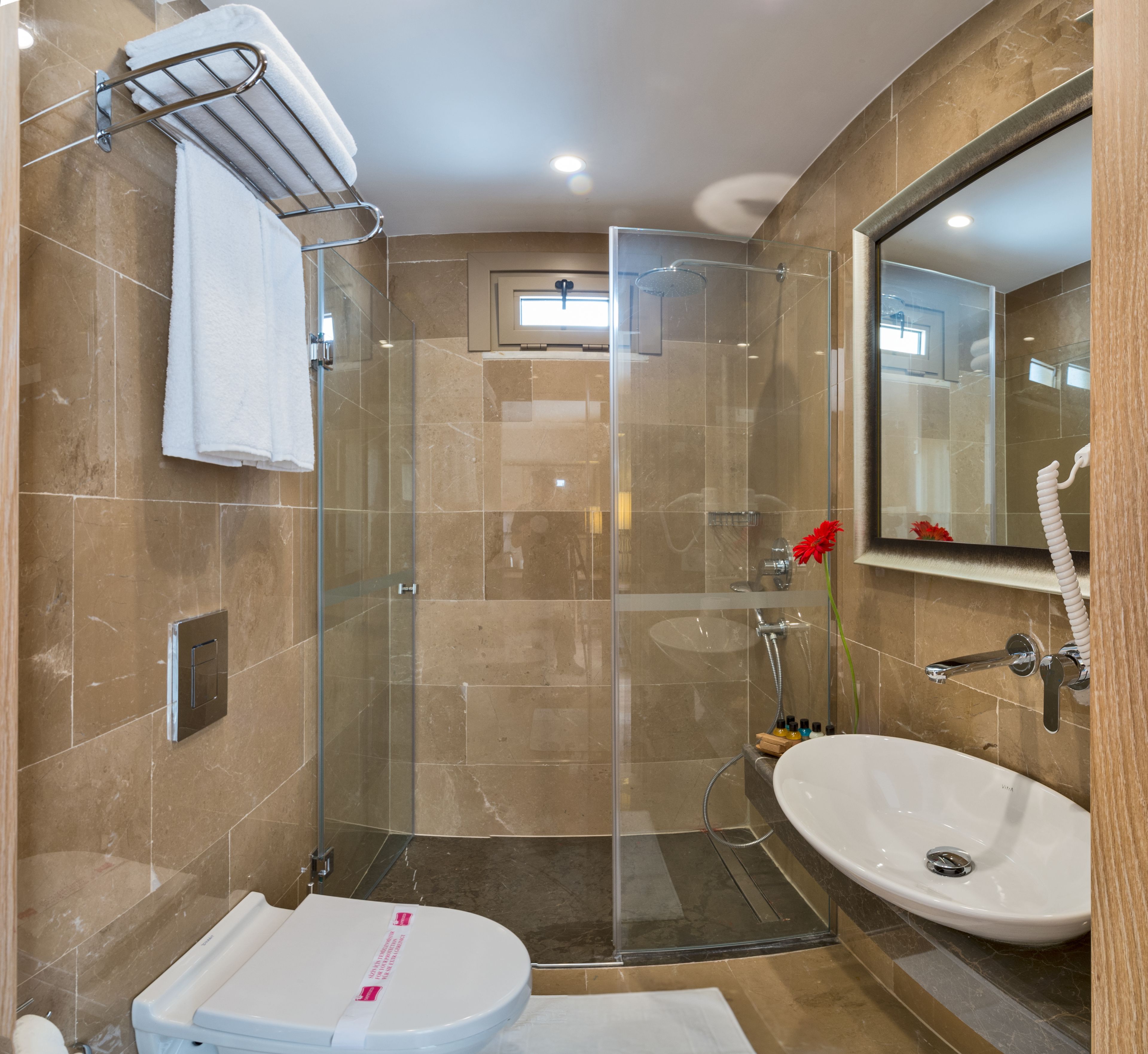 Un baño moderno con ducha de vidrio, lavamanos y retrete.