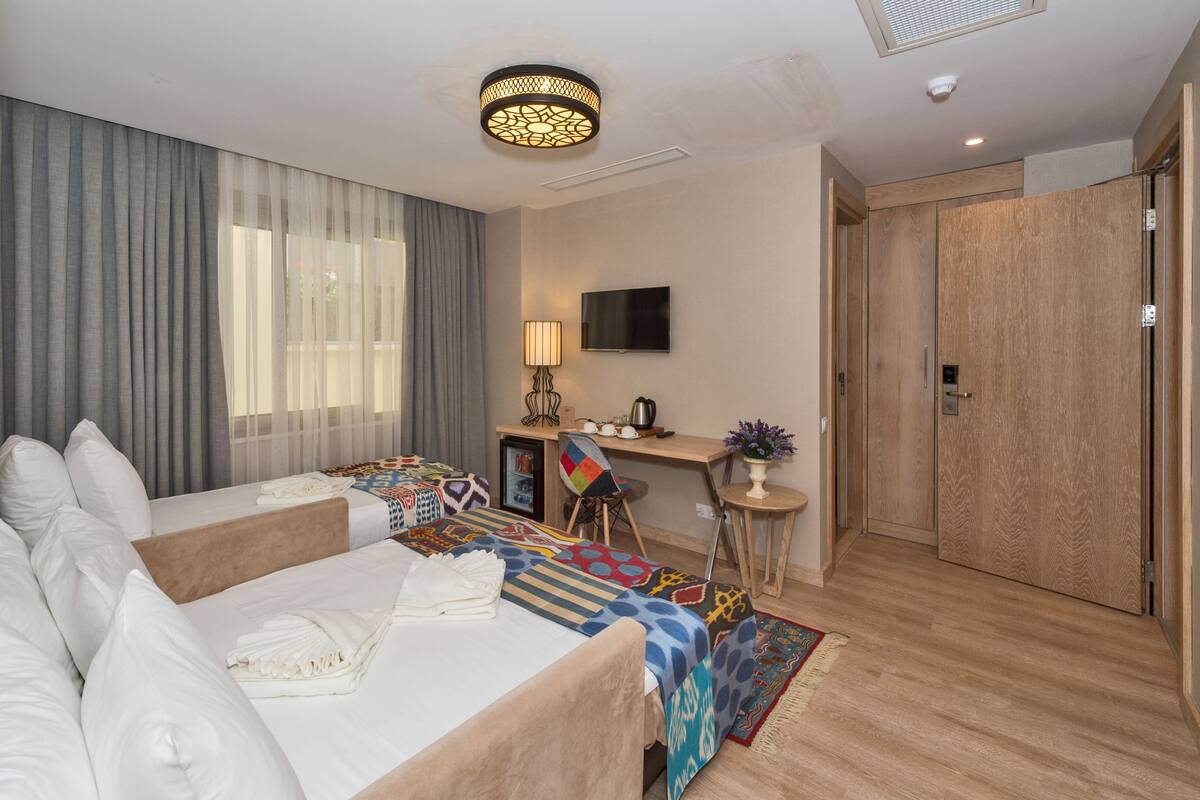 A hotel room with a bed, a desk, a TV, and a wardrobe.
