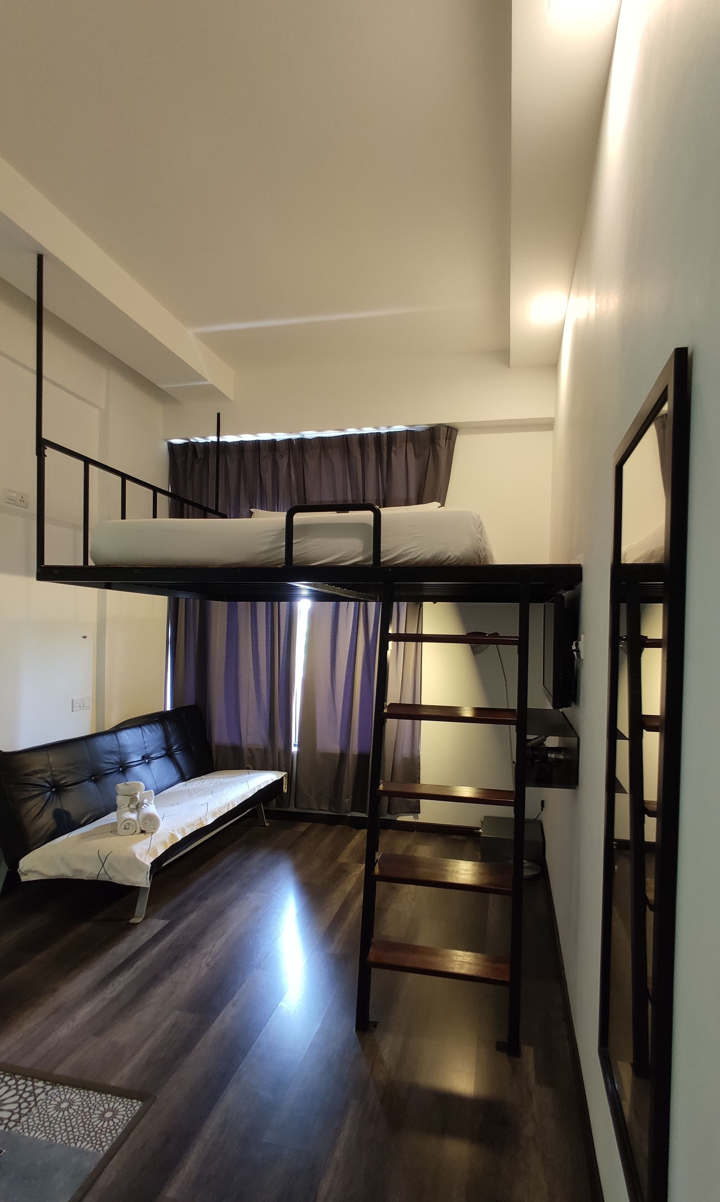 Ein kleines Zimmer mit Etagenbett, Schlafsofa und Tisch.