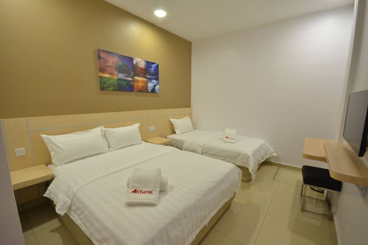 A hotel room with two beds, a TV, and a painting on the wall.
