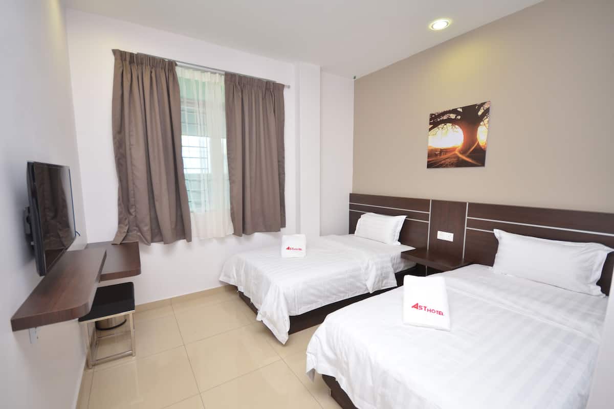 A hotel room with two beds, a desk, a TV, and a window with curtains.