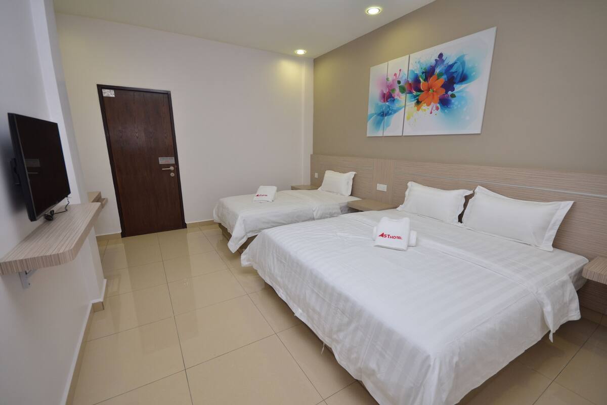 A hotel room with two beds, a TV, and a door.
