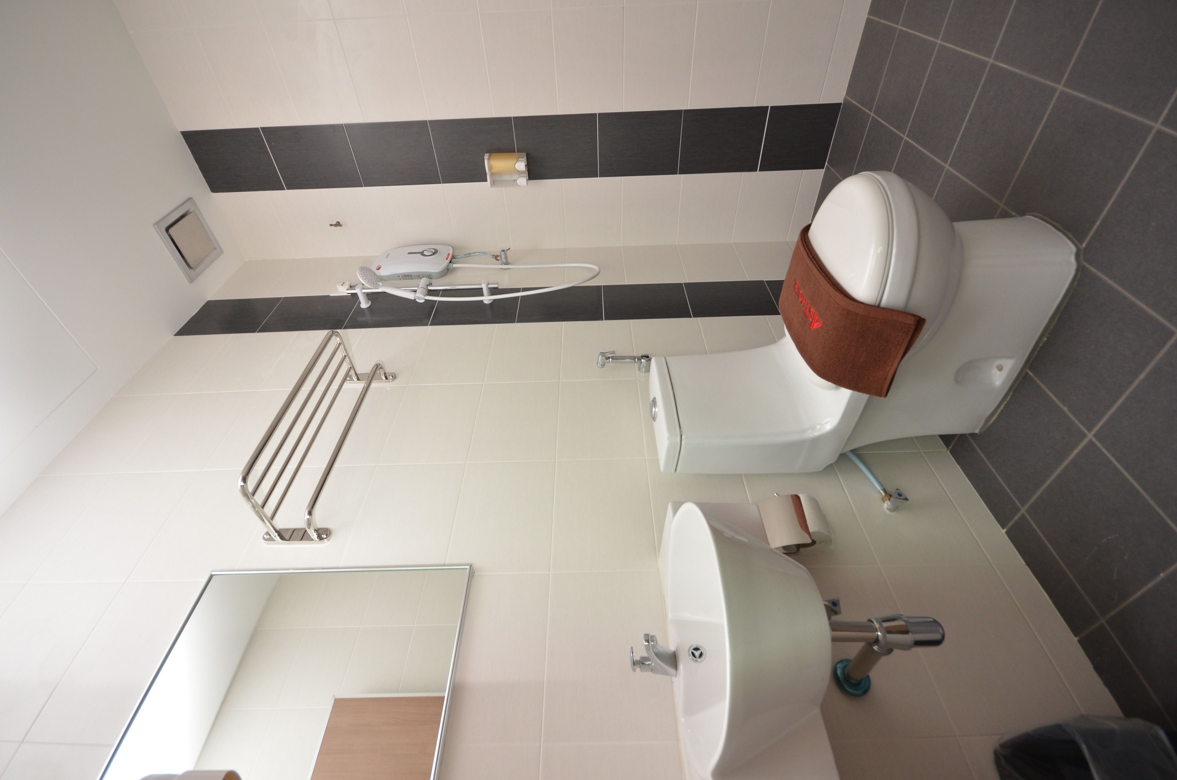Un baño moderno con inodoro, bidé, lavamanos y secamanos.