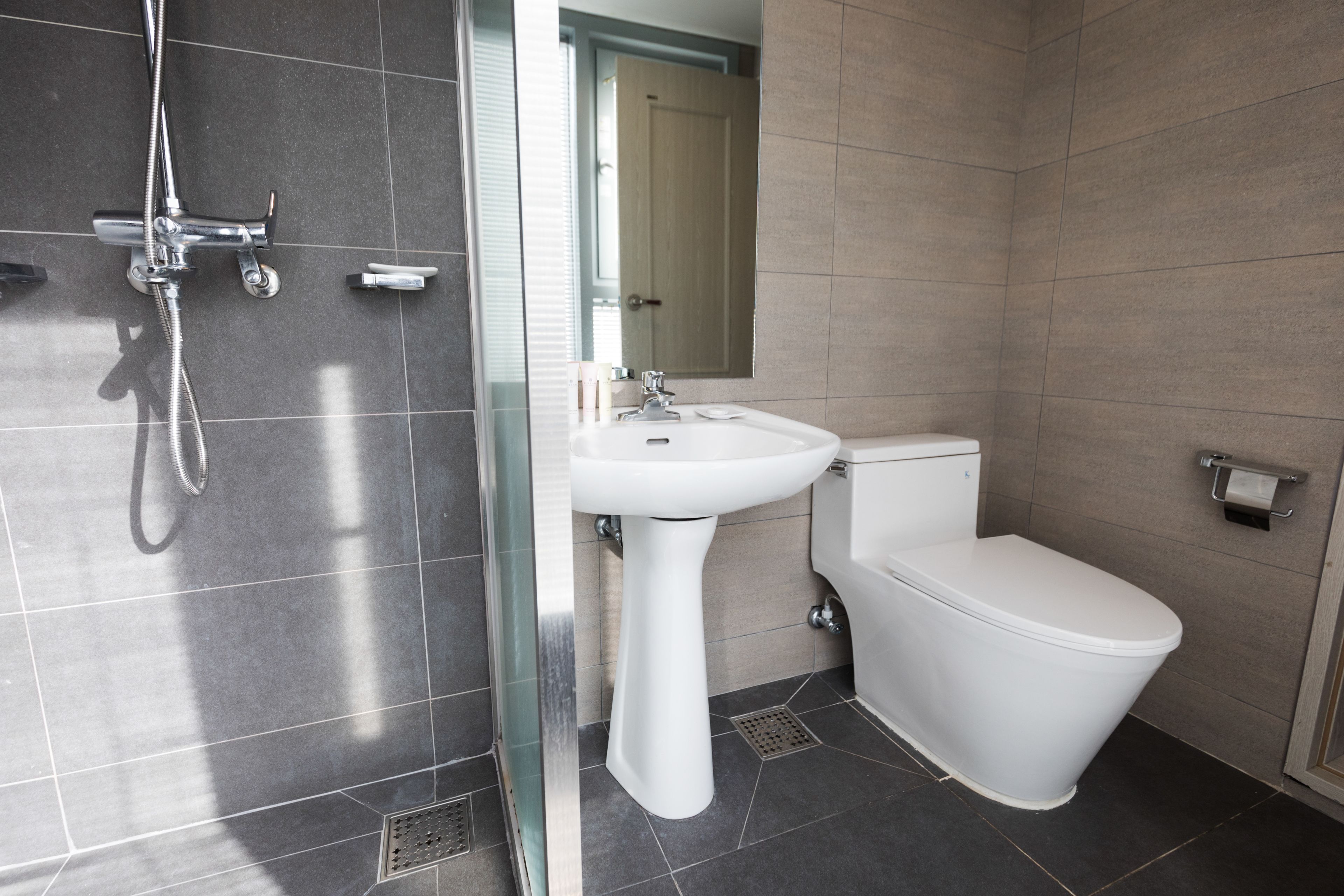A modern bathroom with a shower, sink, and toilet.