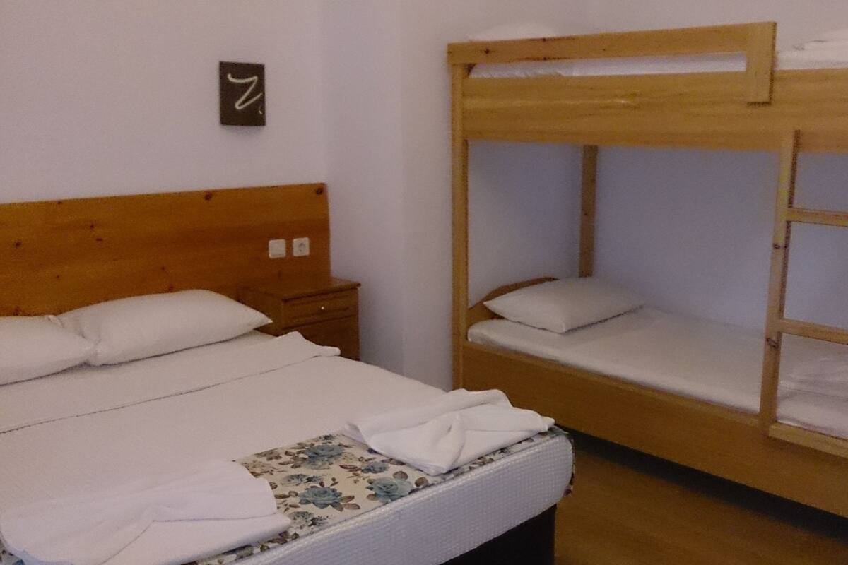 Uma cama beliche com cabeceira de madeira e uma cama de solteiro com colcha estampada com motivos florais.