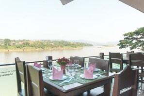 A table set for dining with a view of a river and hills in the background.