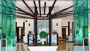 A modern lobby with a central decorative tree, glass walls, and a reception desk. - Namkhong Riverside Hotel Chiang Rai (Chiang Khong)