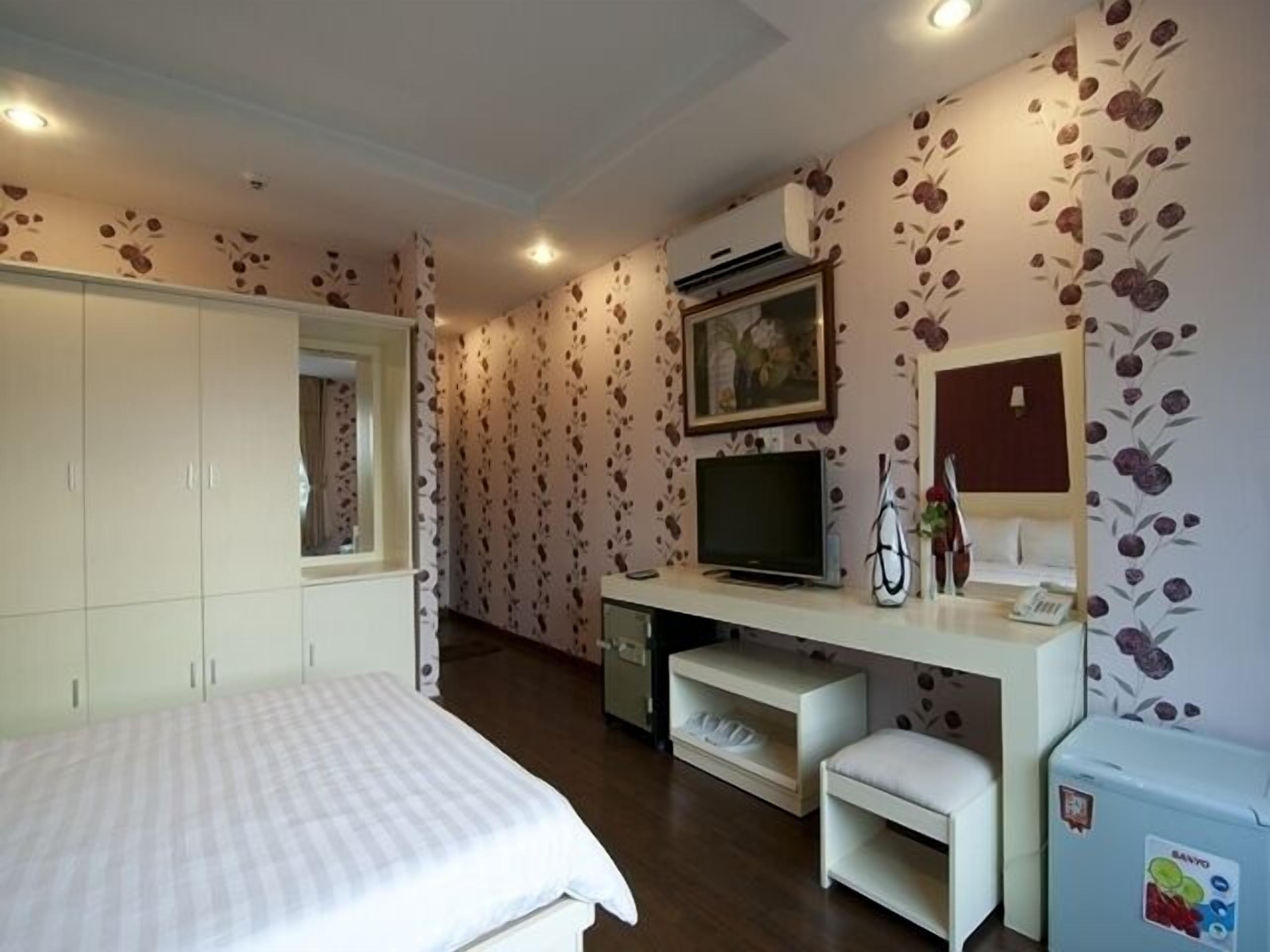 Een slaapkamer met een bed, kast, televisie en een klein bureau met stoel.