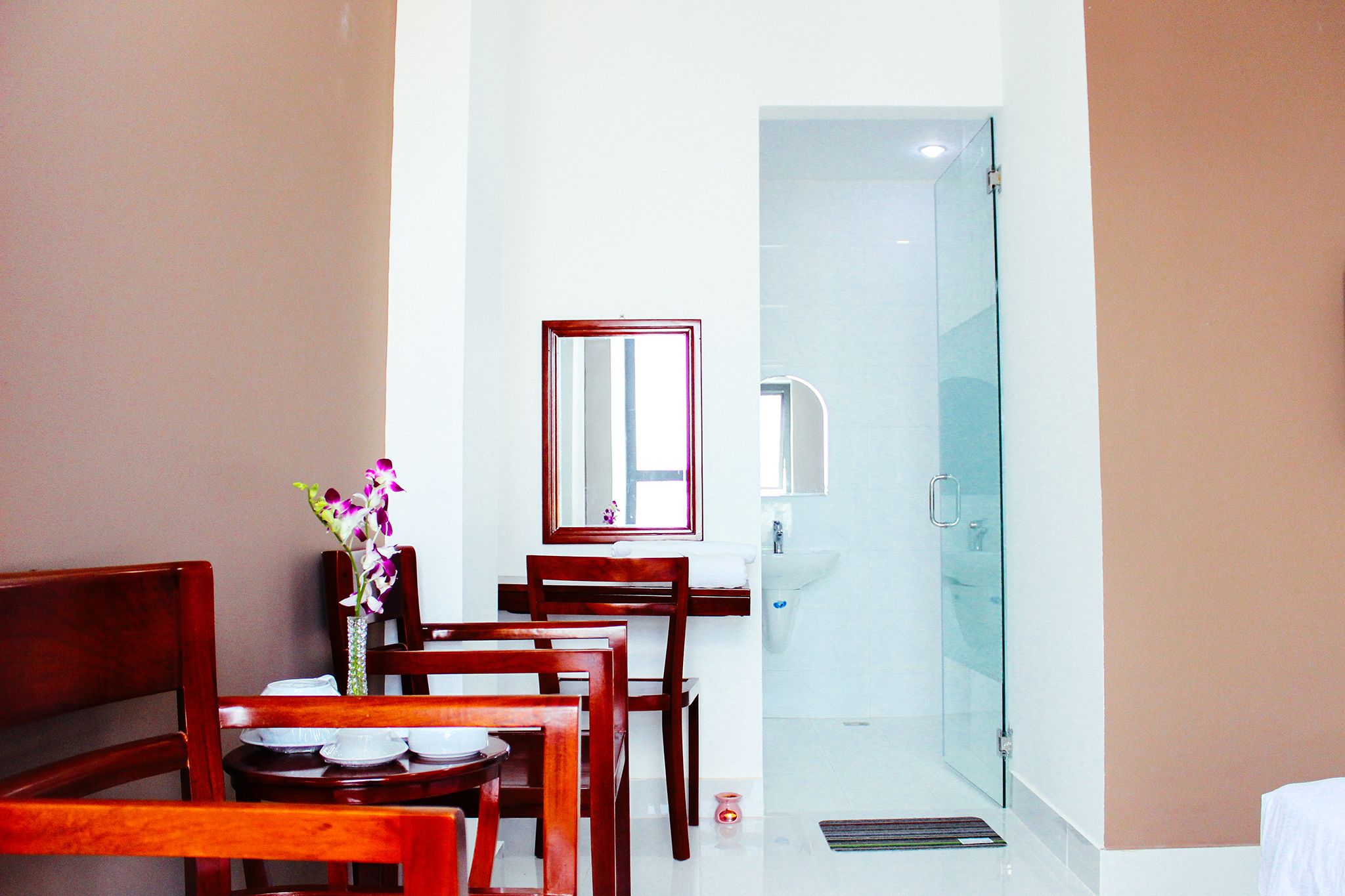 Habitación de hotel con comedor, baño con ducha de vidrio y cama.