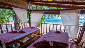 Two massage tables with towels, a bowl, and a small statue, set against a beach view. - Lipe Beach Resort (Koh Lipe)