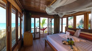 A wooden room with a bed, a small desk, and a view of the ocean. - Lipe Beach Resort (Koh Lipe)