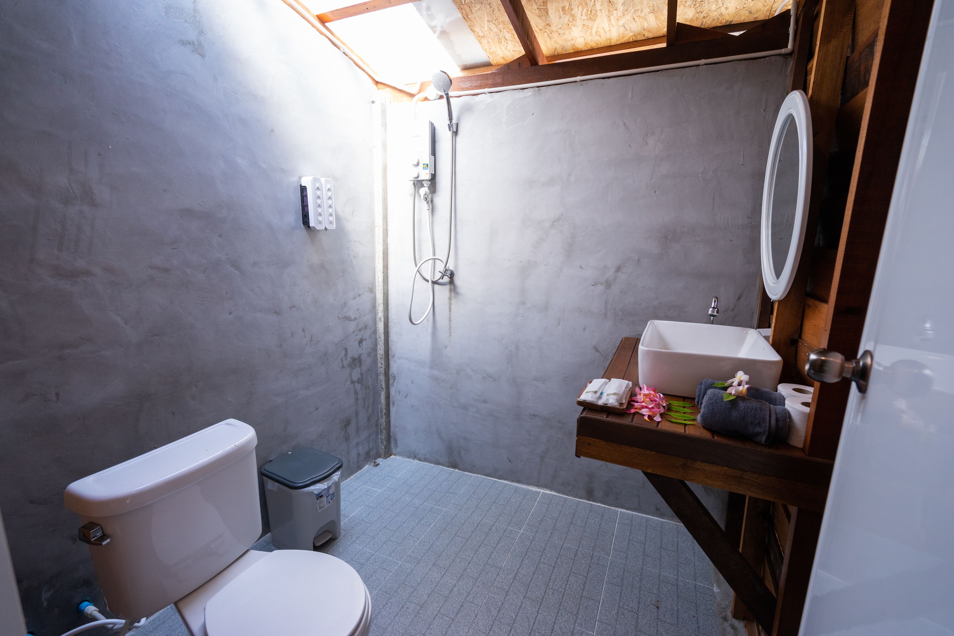 Casa de banho compacta com sanita, chuveiro e zona de lavatório.