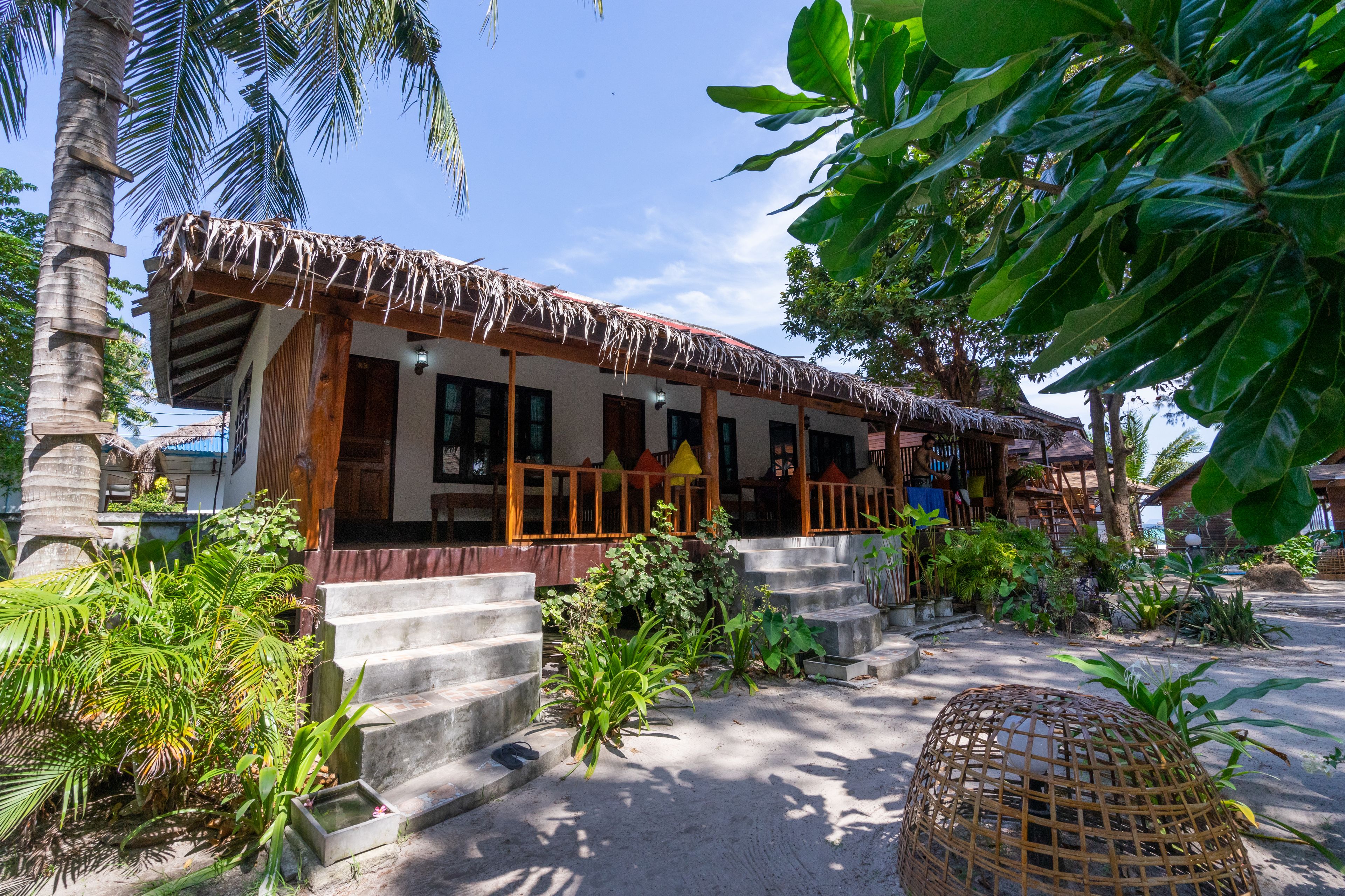 A traditional thatched-roof building with a veranda, surrounded by lush tropical vegetation.