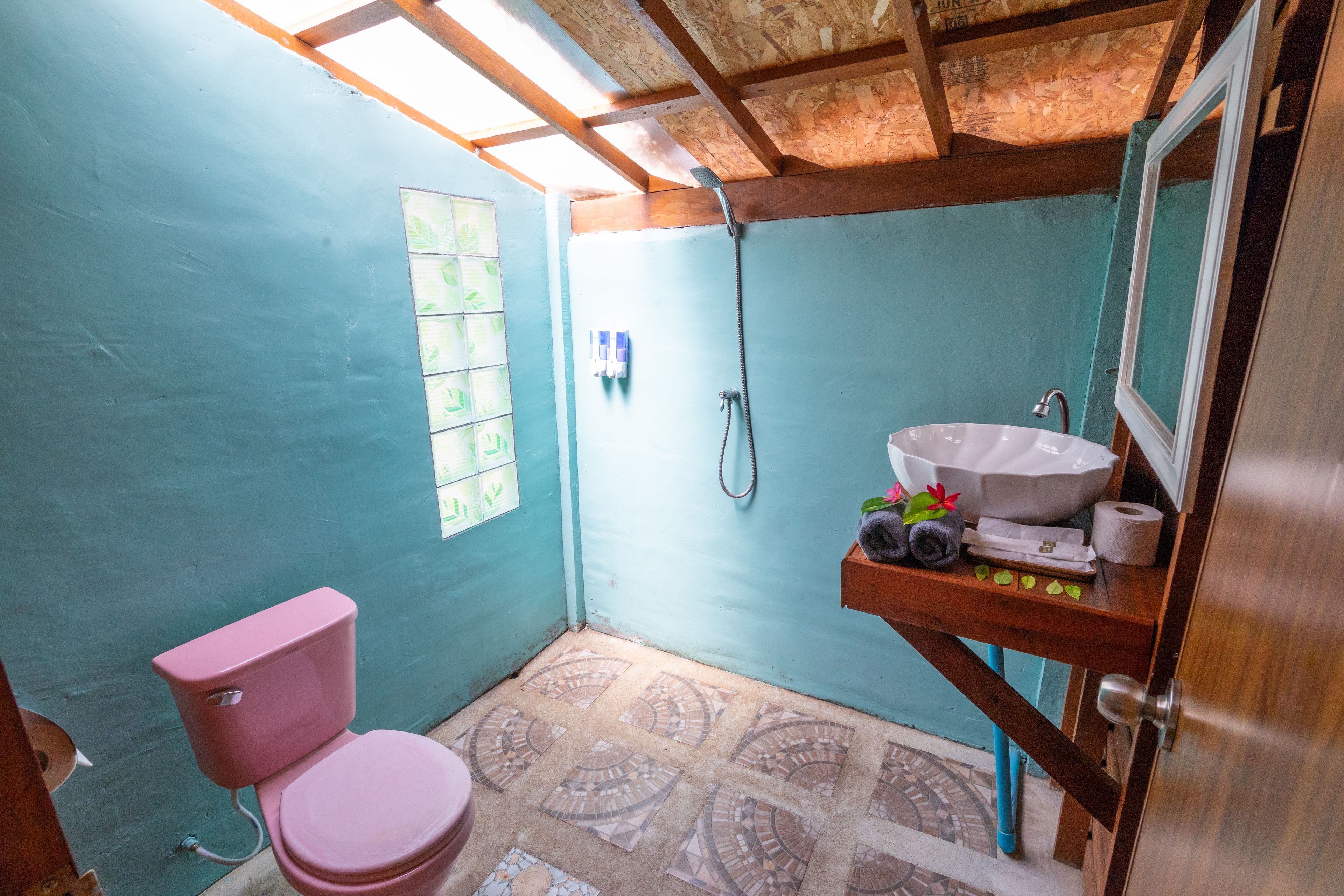 A small bathroom with a pink toilet, a shower, and a sink.