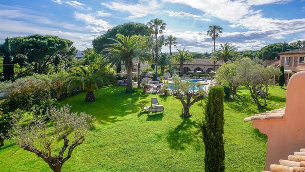 Un jardin luxuriant avec une piscine, des palmiers et un kiosque.