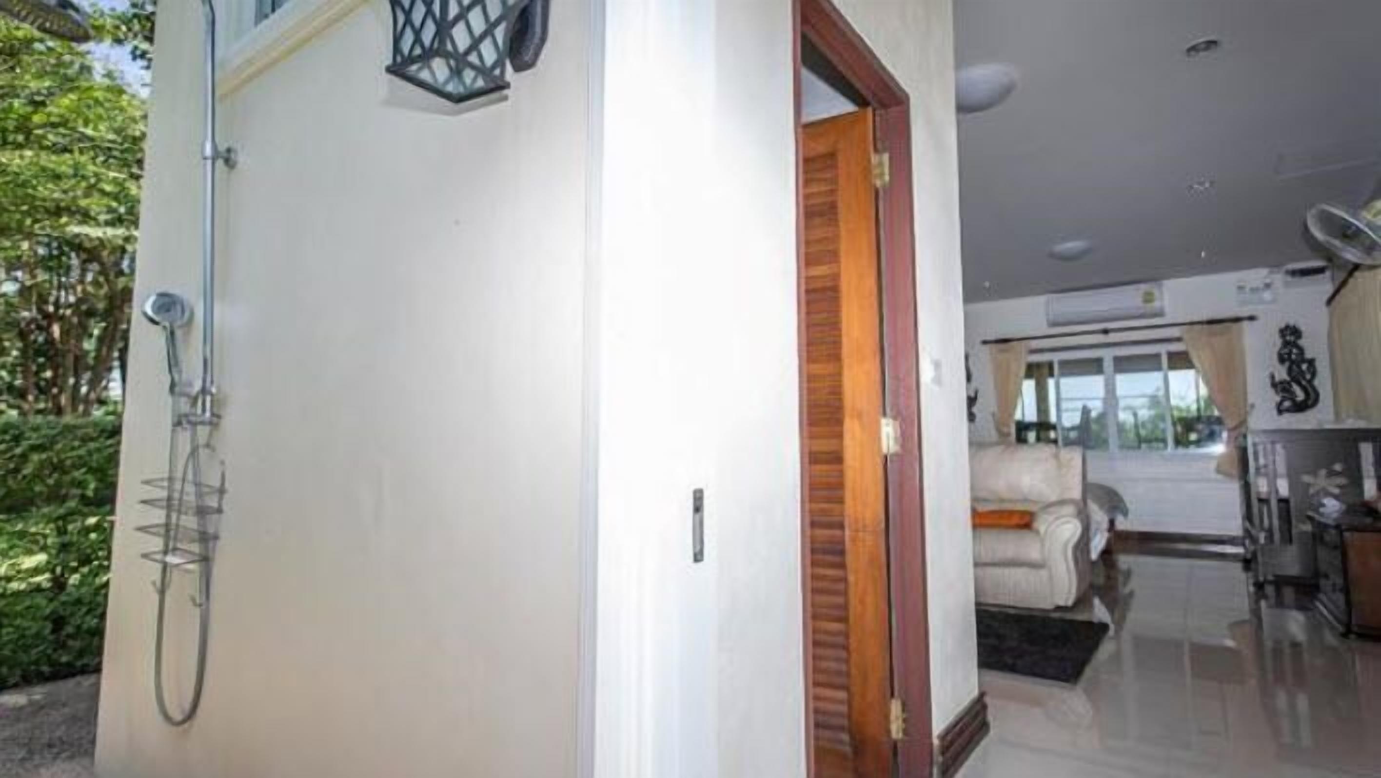 A modern interior with a white door, a wooden door frame, a metal gate, and a glimpse of a living area with a sofa and a table.