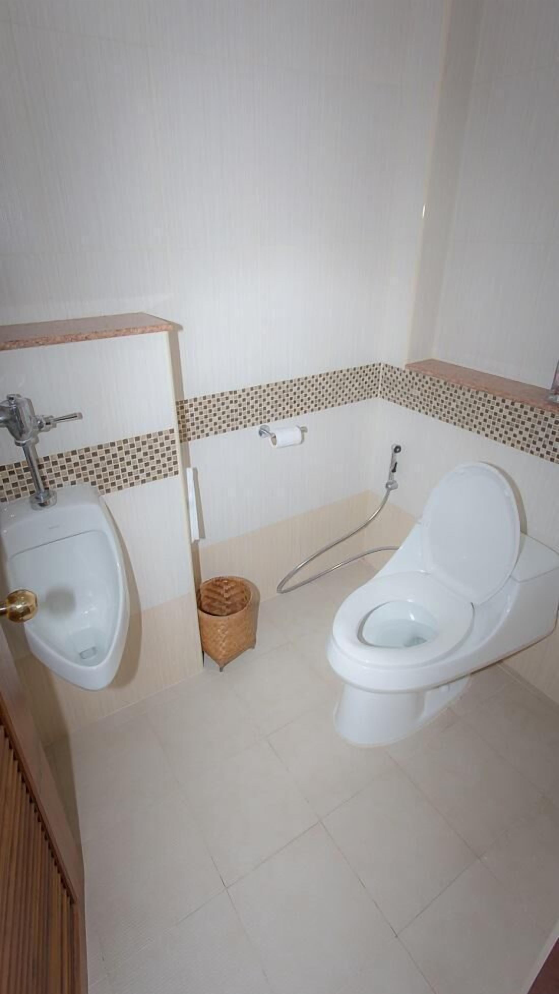 A bathroom with a urinal, toilet, and a small trash bin.