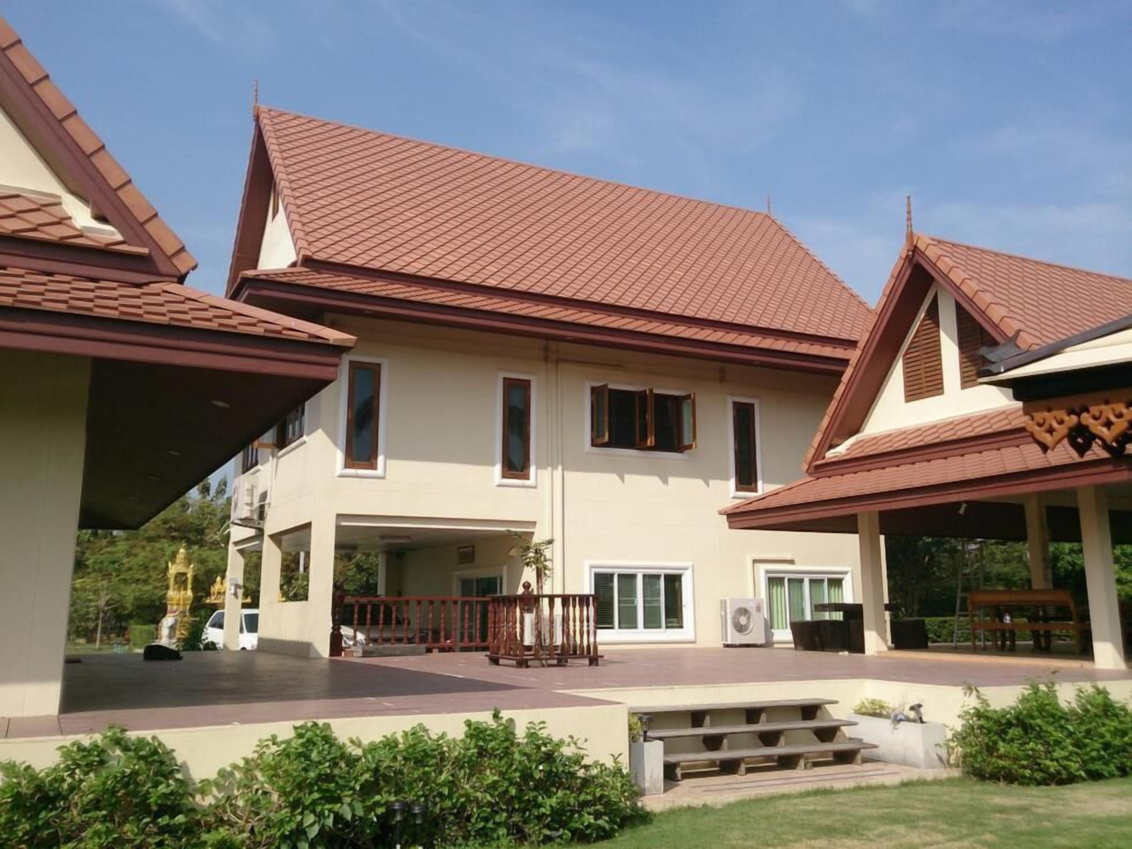 A two-story house with a tiled roof, a covered porch, and a front entrance with a bench.