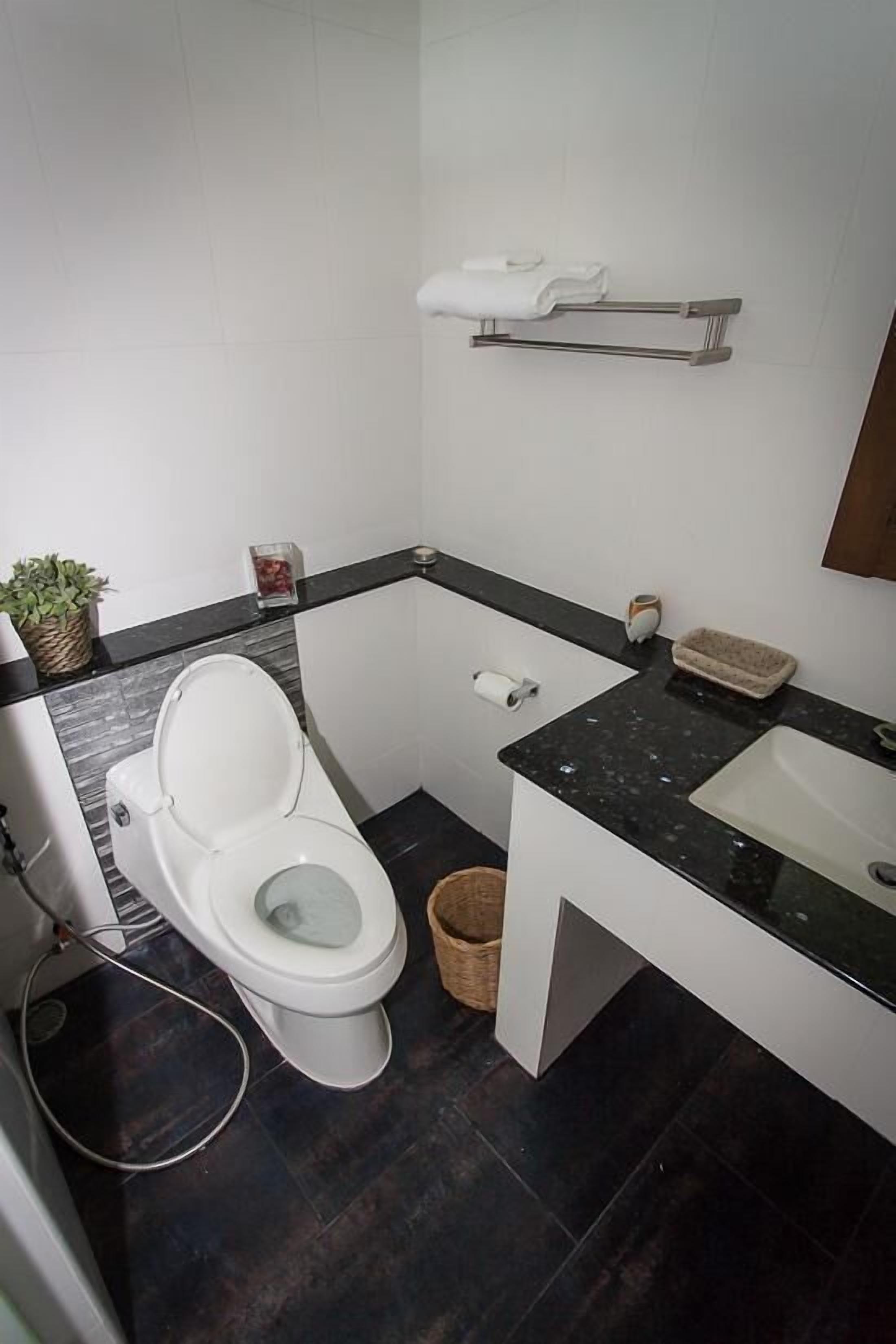 A compact bathroom with a white toilet, a sink, and a small shelf above the sink.