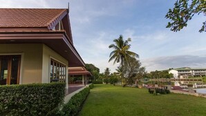 A building with a tiled roof, a covered outdoor area, and a well-maintained lawn.