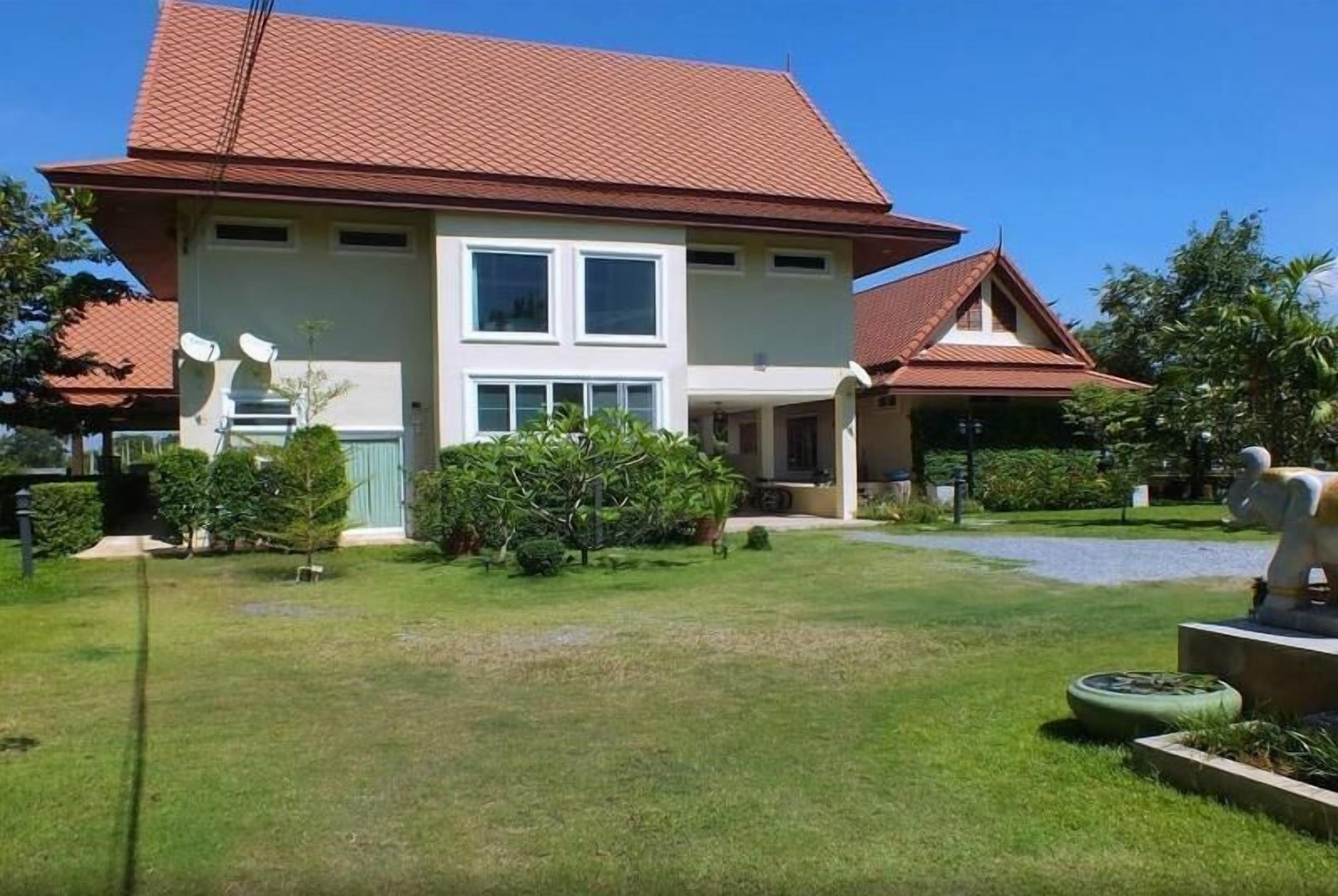 Ein zweistöckiges Haus mit roten Ziegeln, einem gepflegten Rasen und einem kleinen Garten mit einer Statue.