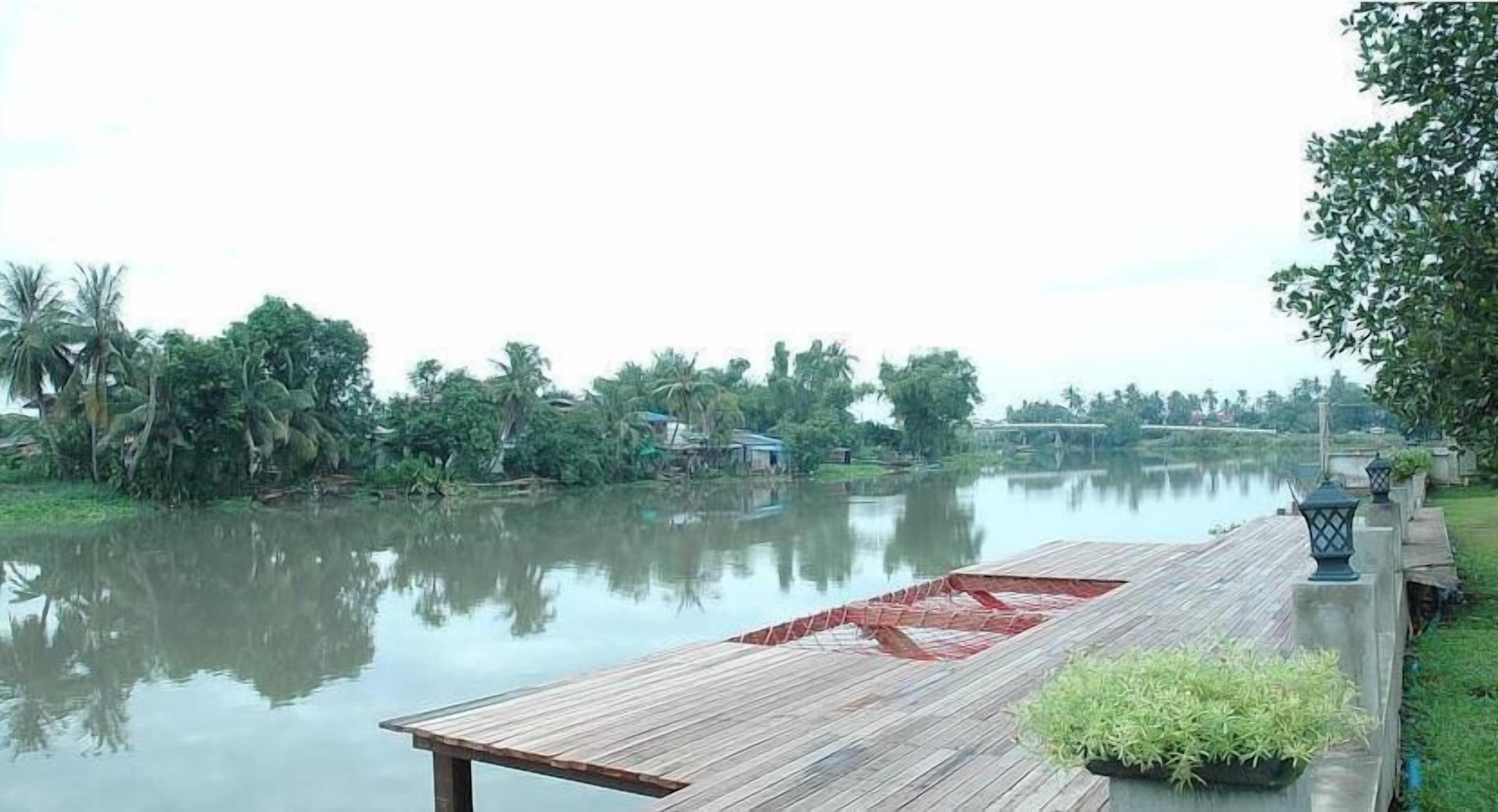 A wooden dock extending over calm water, surrounded by lush greenery and trees.