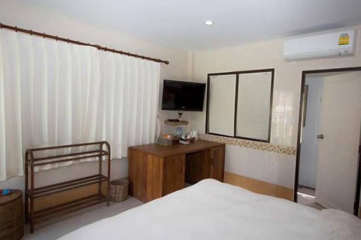 Ein Hotelzimmer mit Bett, Schreibtisch aus Holz, Fernseher und Kleiderschrank.