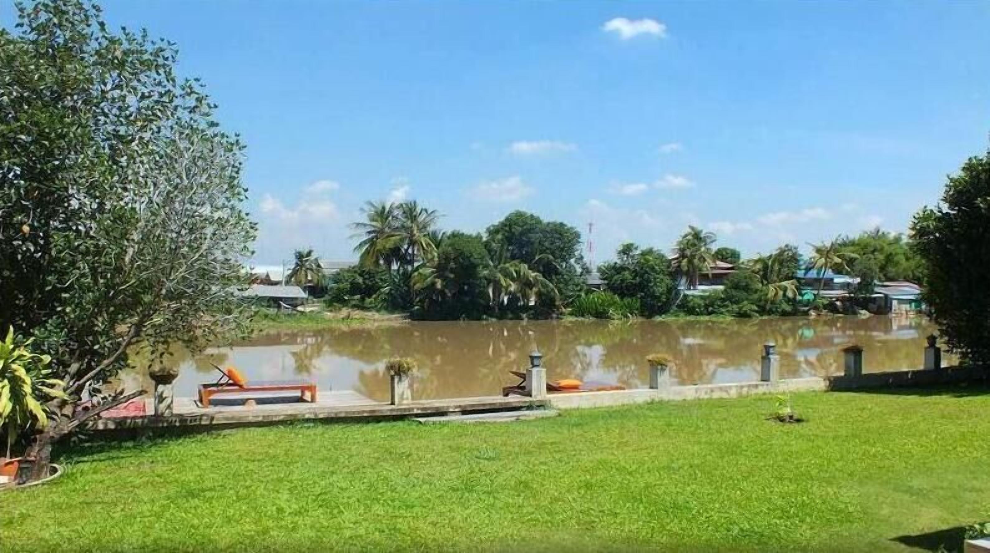 A grassy area with a pond, a wooden dock, and a small boat.