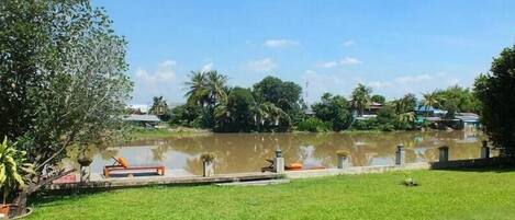 A grassy area with a pond, a wooden dock, and a small boat.