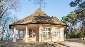 A small, single-story building with a conical roof, white columns, and large windows.