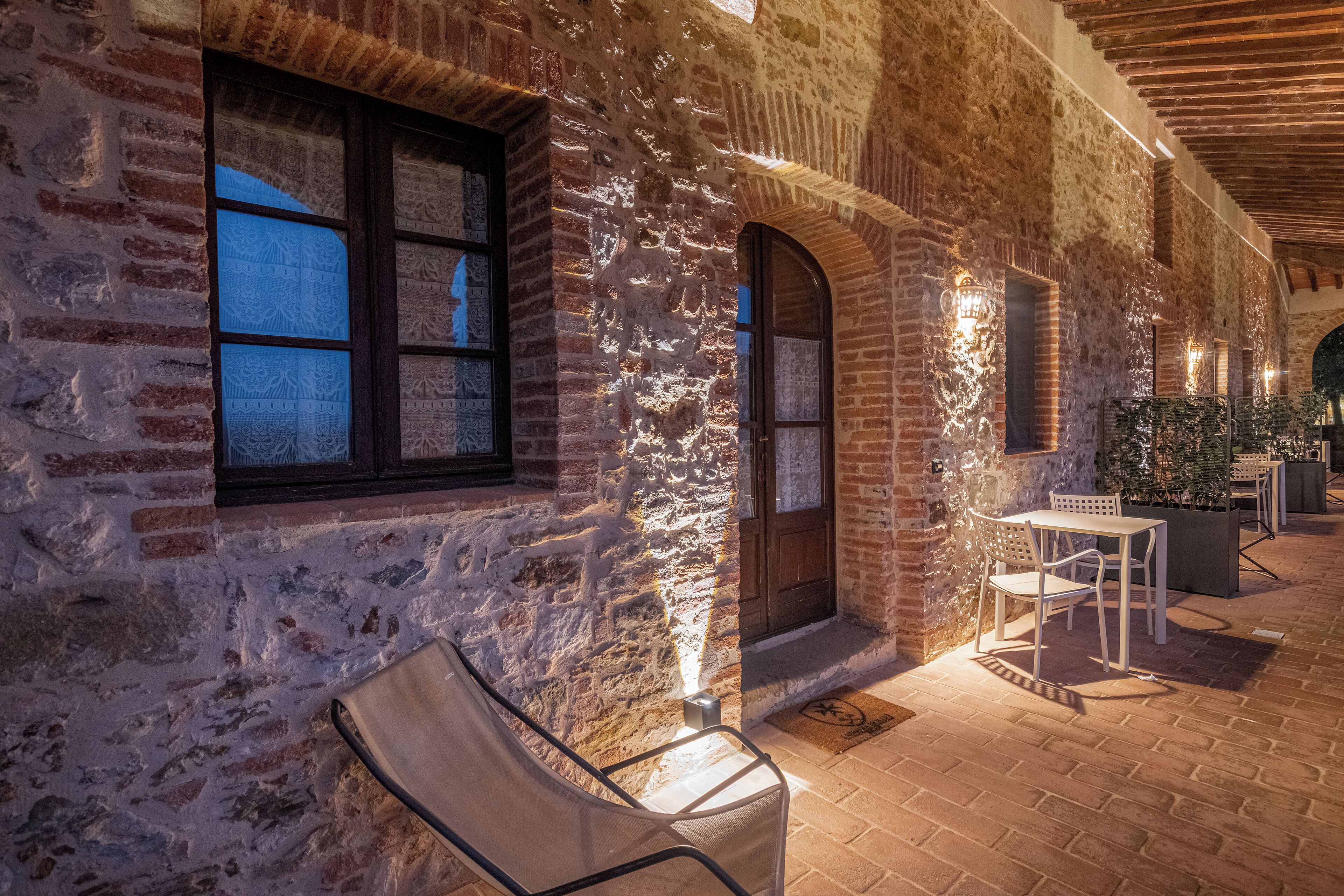 Un bâtiment rustique en briques, doté d’arcades et d’un patio couvert avec des sièges pour l’extérieur.