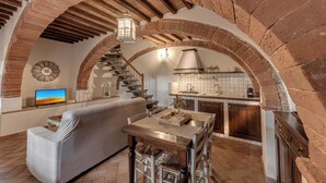 Un salon confortable avec un canapé, un téléviseur et une table à manger avec des chaises. Il y a également un coin cuisine équipé d'une cuisinière et d'un évier.