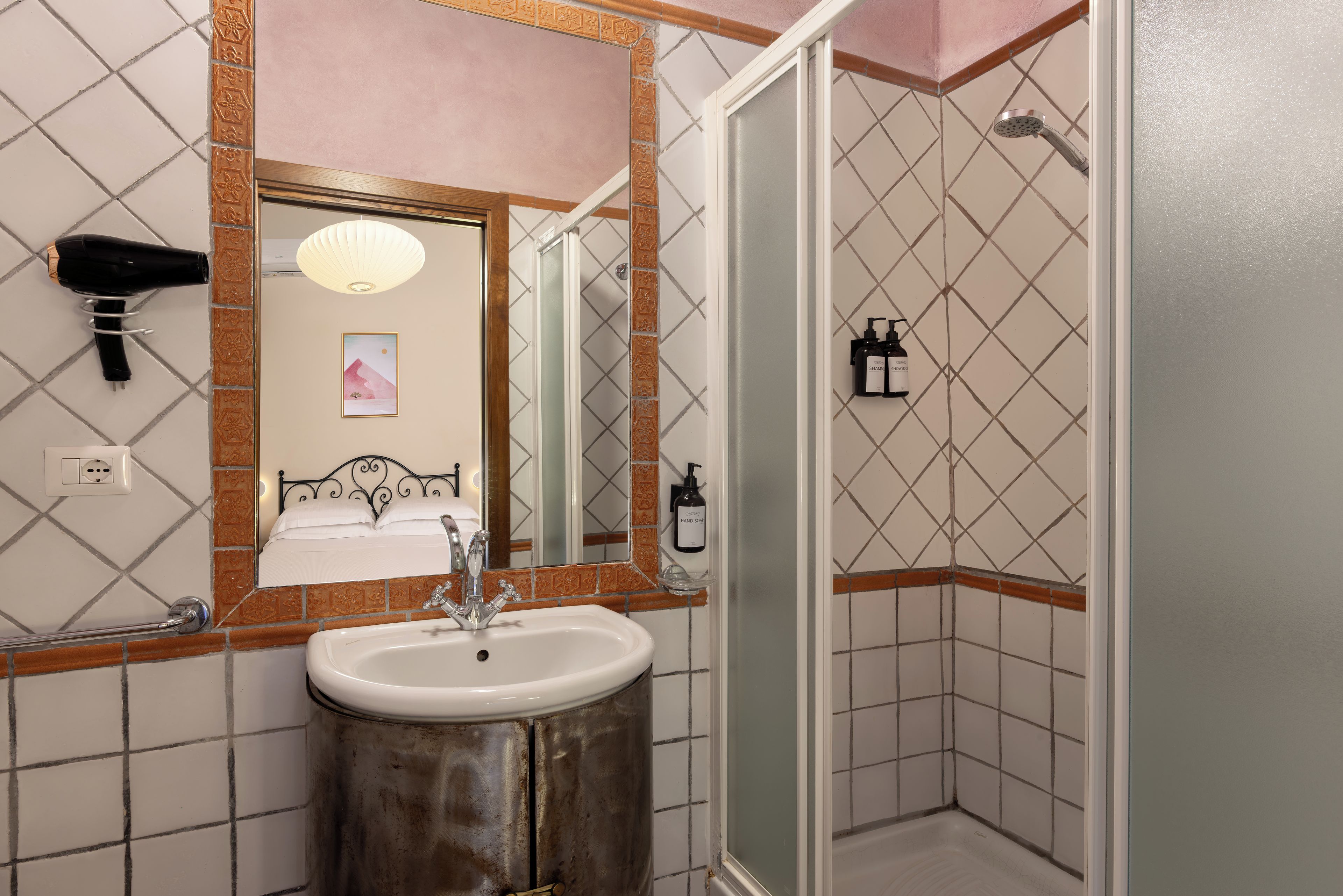 A bathroom with a sink, mirror, and shower.