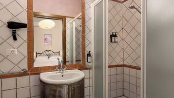A bathroom with a sink, mirror, and shower.