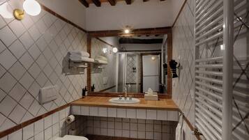 A bathroom with a toilet, sink, mirror, towel rack, and a shower area.