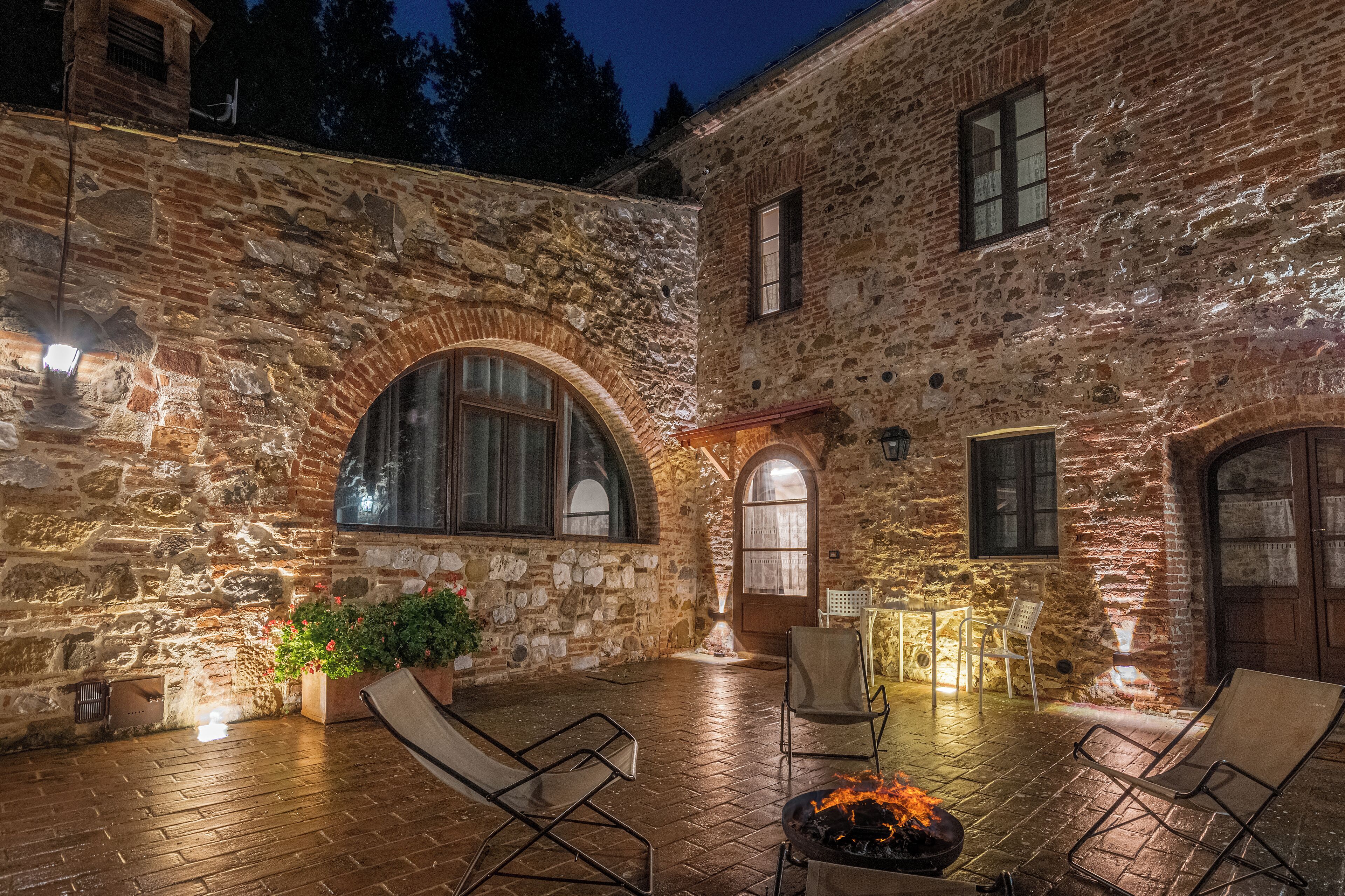 A stone building with arched windows and a fire pit in the center.