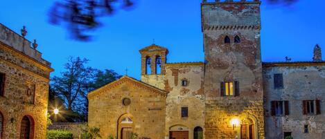 Un edificio histórico con una torre de campanas, arcos en las puertas y un patio.