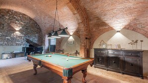 A billiards room with a pool table, a piano, and a brick wall. - Abbadia Sicille Relais (Trequanda)