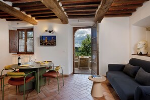 Habitación con zona de comedor, sofá y vistas al exterior.