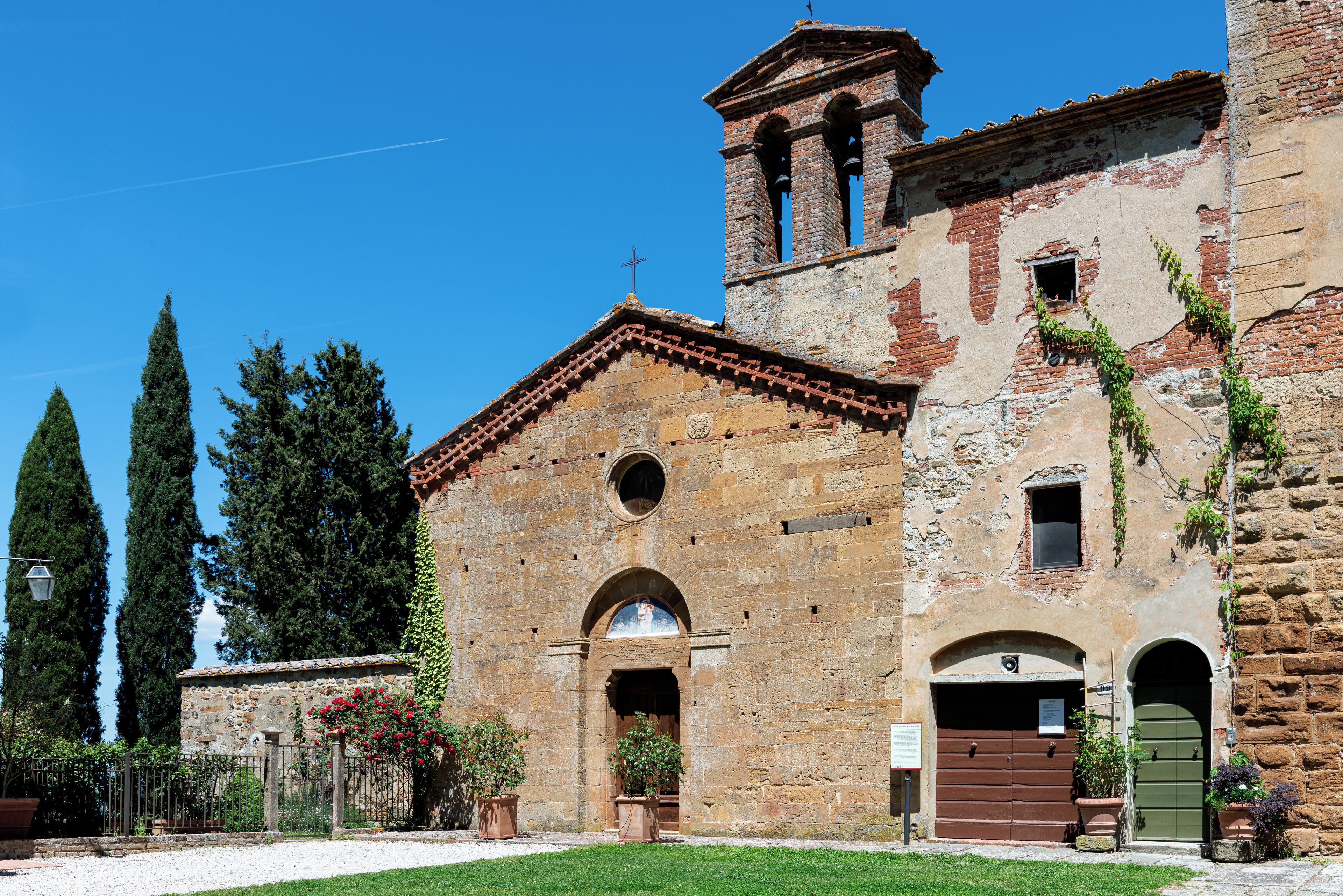 Un bâtiment historique doté d’un clocher, de fenêtres en arc et d’une entrée fermée par un portail.
