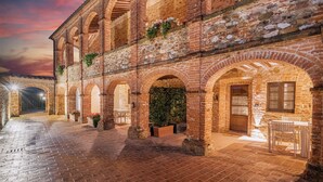 A courtyard with brick arches, potted plants, and outdoor seating. - Abbadia Sicille Relais (Trequanda)
