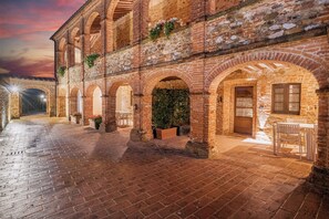 Un cortile con archi in mattoni, piante in vaso e posti a sedere all'aperto.
