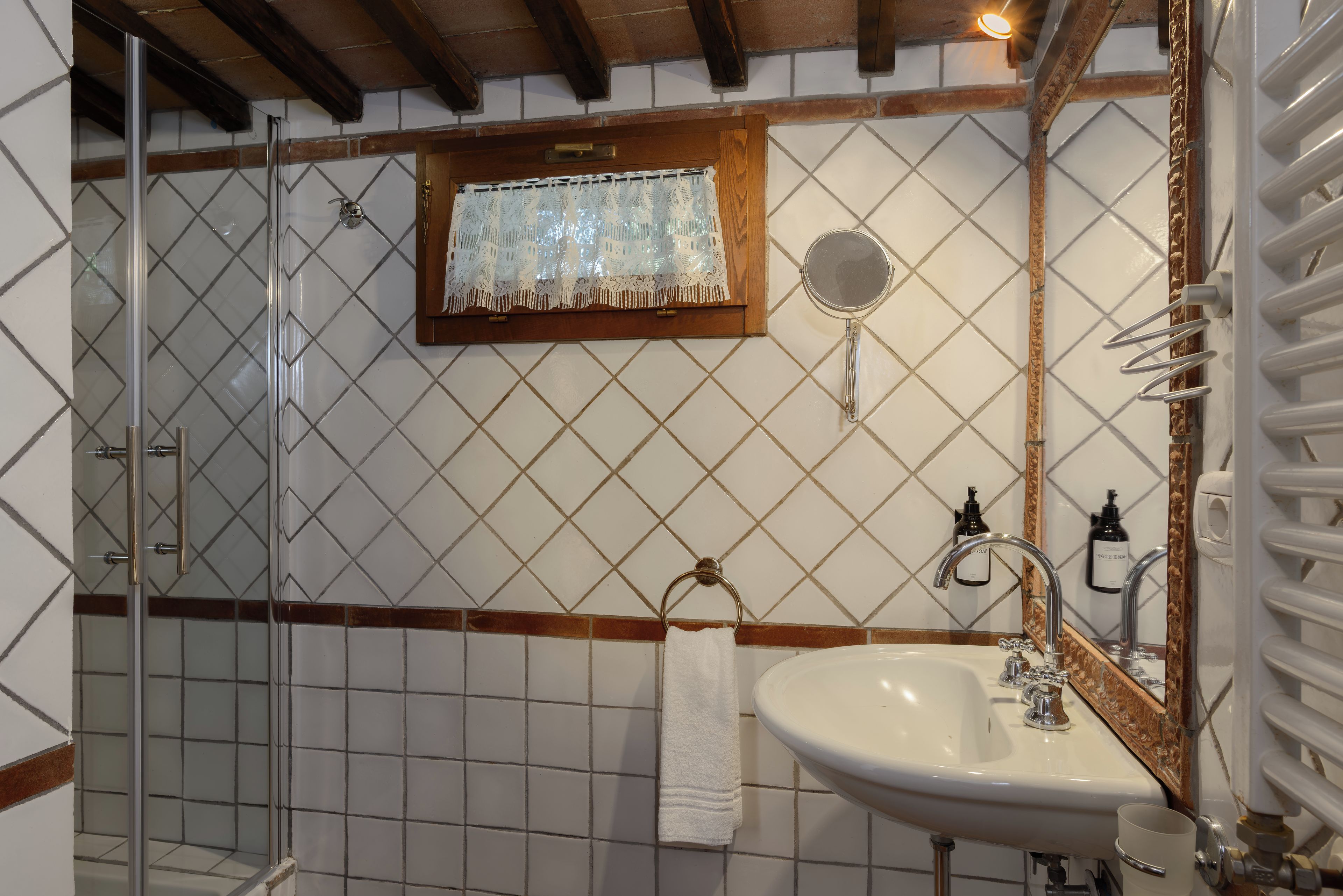 Une salle de bain avec une douche à parois de verre, un lavabo avec un miroir et un porte-serviettes.