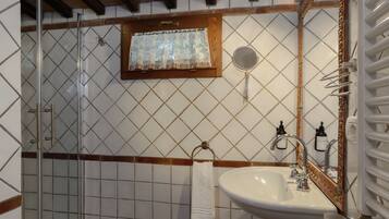 Une salle de bain avec une douche à parois de verre, un lavabo avec un miroir et un porte-serviettes.