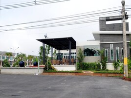 A modern building with a covered outdoor seating area, surrounded by greenery and palm trees.