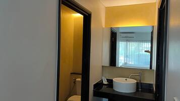 A compact bathroom with a white toilet, a black sink, and a mirror above the sink.
