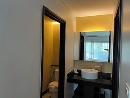 A compact bathroom with a white toilet, a black sink, and a mirror above the sink.