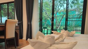 Habitación de hotel con una cama grande, un escritorio y vistas a zonas verdes.