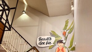 A staircase with a handrail, a wall mural featuring a child and a dog, and a sign with text. - The Hive Hatyai Hostel (Hat Yai)