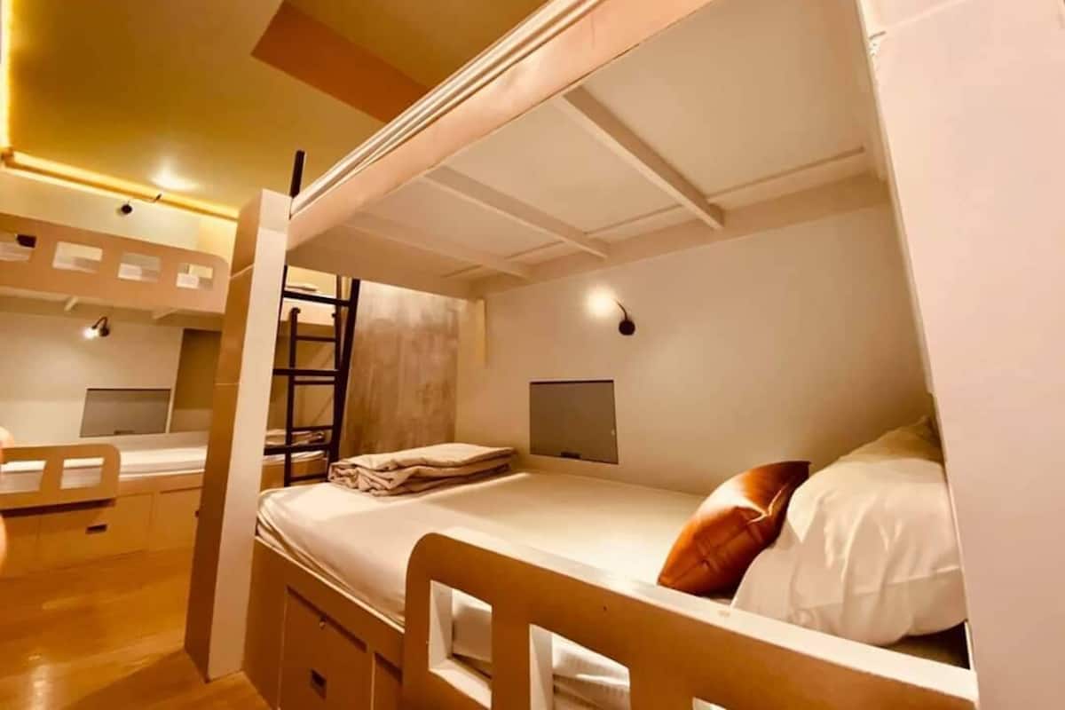 A bunk bed room with a desk and a chair.